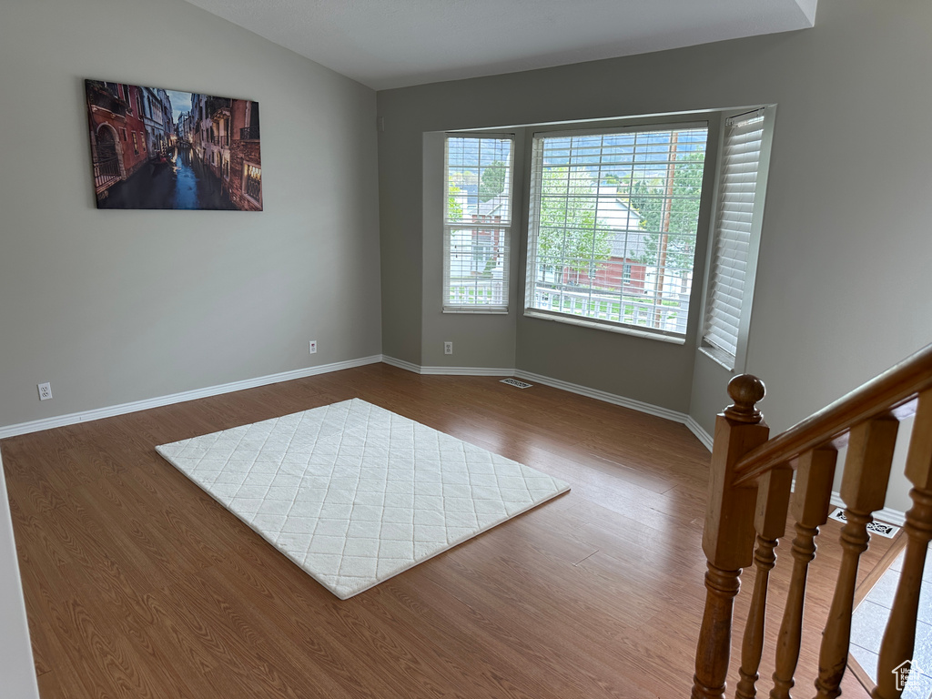 Unfurnished room with baseboards, lofted ceiling, and wood finished floors