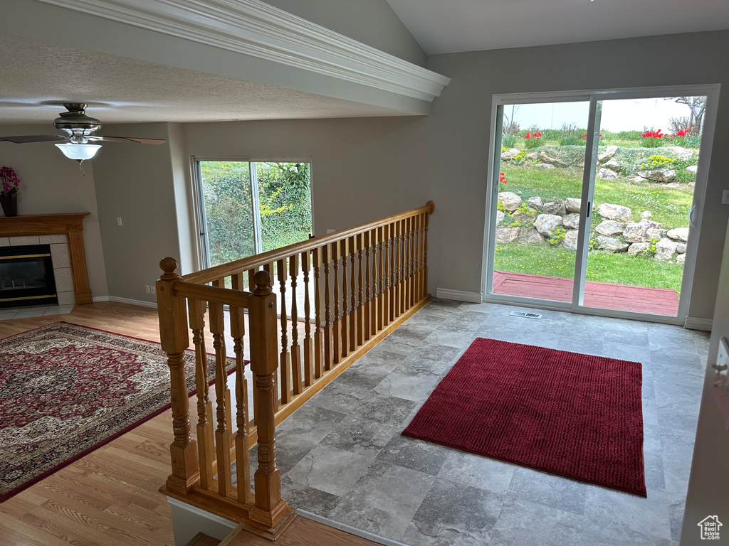 Staircase featuring a fireplace, vaulted ceiling, a ceiling fan, and baseboards