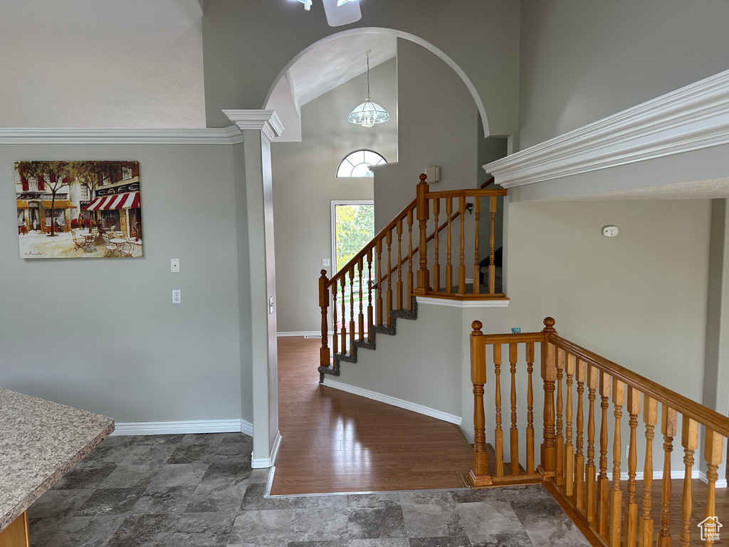Staircase featuring stone finish floor, baseboards, arched walkways, and high vaulted ceiling