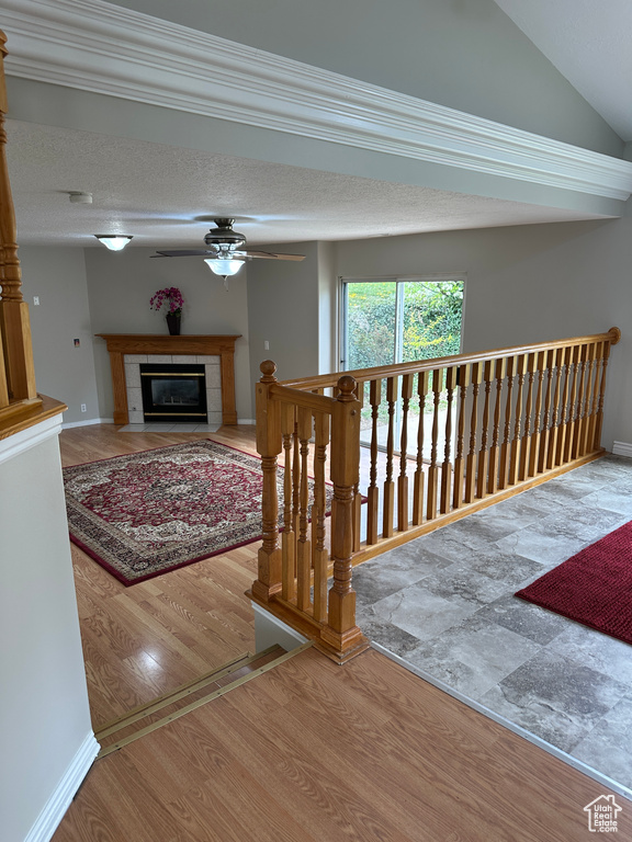 Interior space featuring vaulted ceiling, wood finished floors, ceiling fan, a tiled fireplace, and baseboards