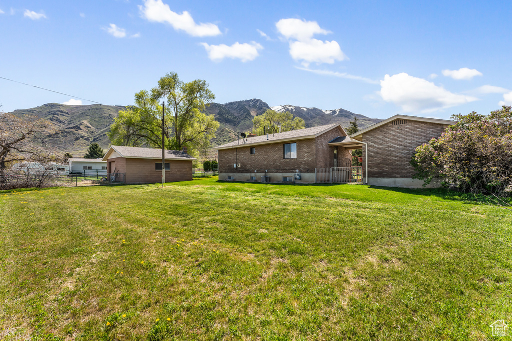 Back of property featuring brick siding, a yard, fence, and a mountain view