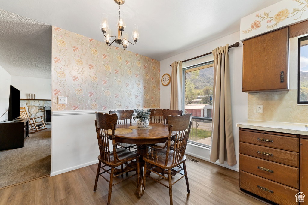 Dining area with light wood-type flooring, plenty of natural light, and an inviting chandelier