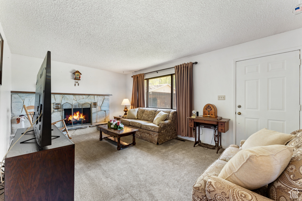 Living area with carpet floors, a textured ceiling, and a fireplace