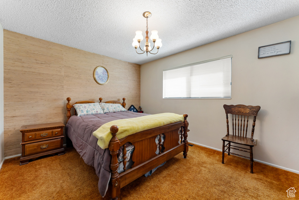 Carpeted bedroom featuring a textured ceiling, baseboards, and an inviting chandelier