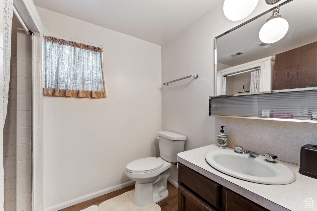 Full bath with a tile shower, visible vents, toilet, vanity, and baseboards