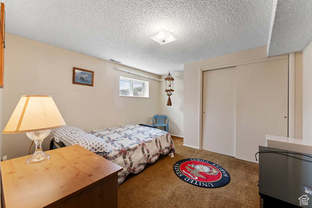 Bedroom with carpet floors, a textured ceiling, visible vents, and a closet