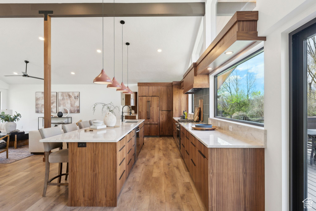 Kitchen with a sink, brown cabinetry, light wood-type flooring, modern cabinets, and a kitchen bar