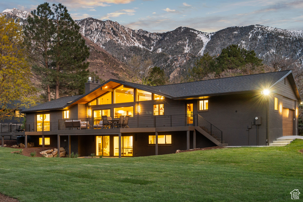 Back of house featuring stairway, a deck with mountain view, and a yard