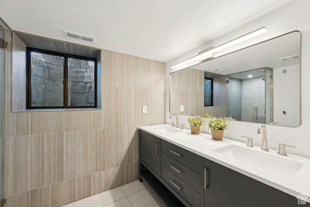 Bathroom with a sink, visible vents, and tile walls