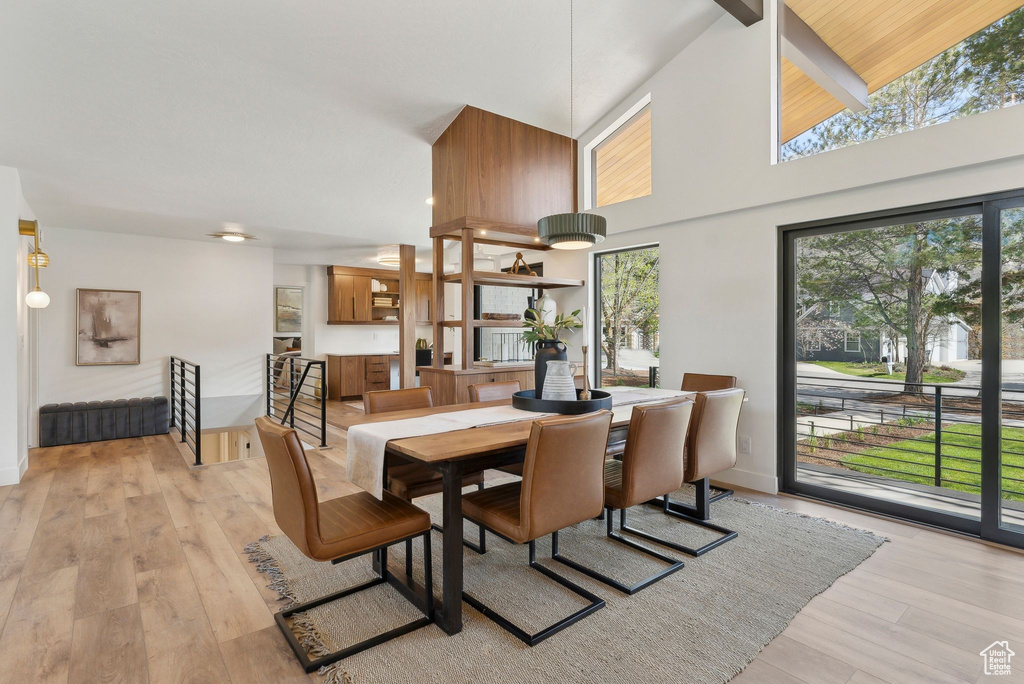 Dining room featuring light wood finished floors, baseboards, and a towering ceiling