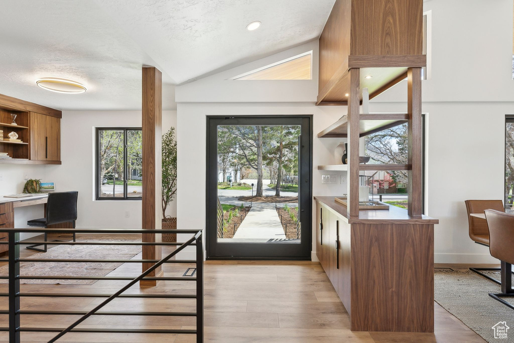 Interior space featuring light wood-type flooring, plenty of natural light, built in study area, and a textured ceiling