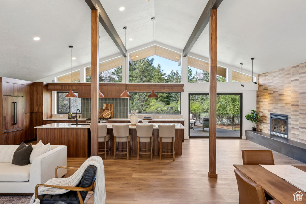 Living room with beamed ceiling, light wood-type flooring, a fireplace, and plenty of natural light