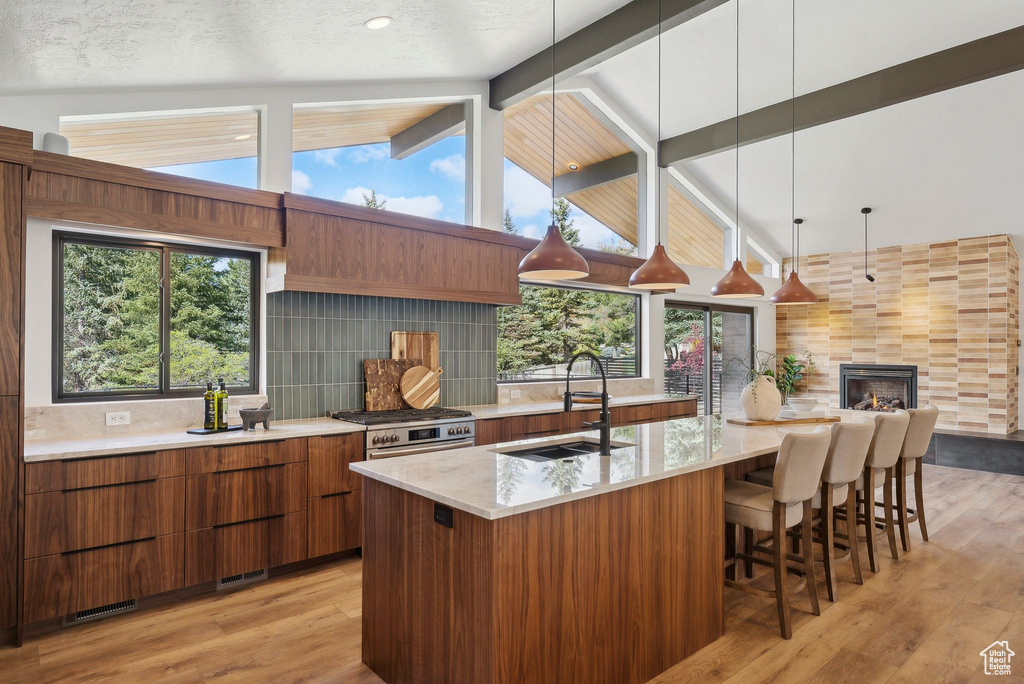 Kitchen featuring a sink, brown cabinetry, lofted ceiling with beams, modern cabinets, and light wood finished floors