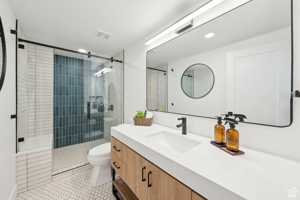 Full bathroom with a shower stall, vanity, toilet, tile patterned flooring, and visible vents