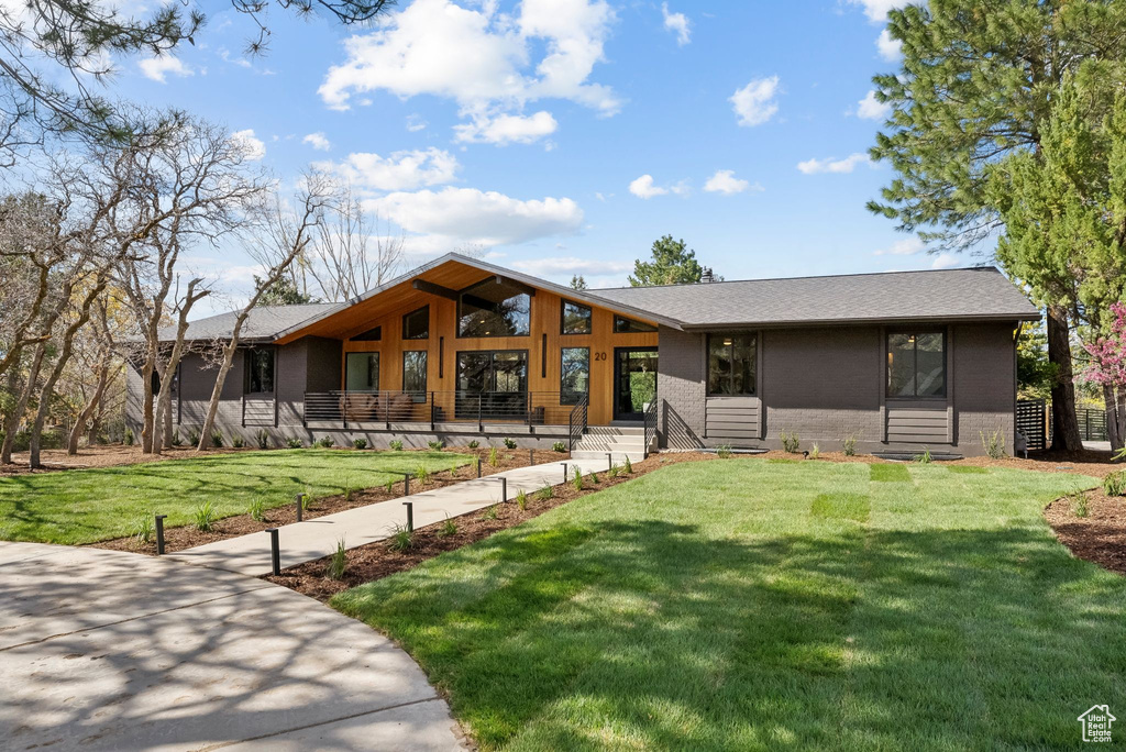 View of front of house with brick siding, roof with shingles, and a front lawn