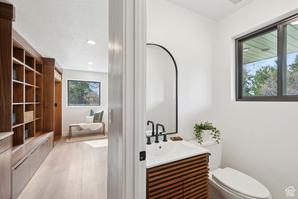 Bathroom featuring wood finished floors, vanity, recessed lighting, and toilet