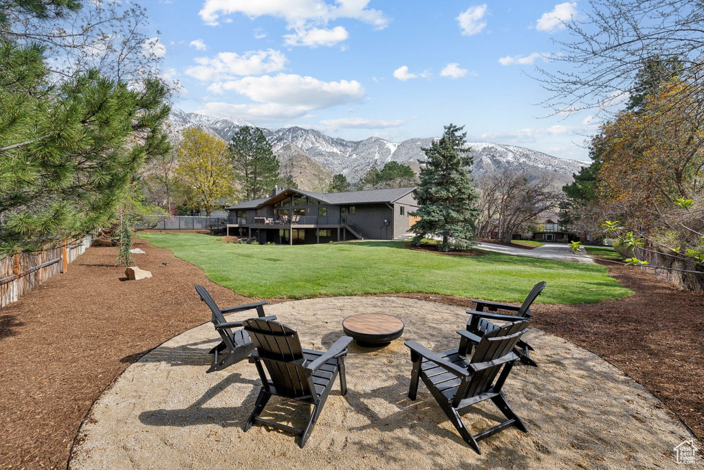 View of yard featuring fence, an outdoor fire pit, and a deck with mountain view