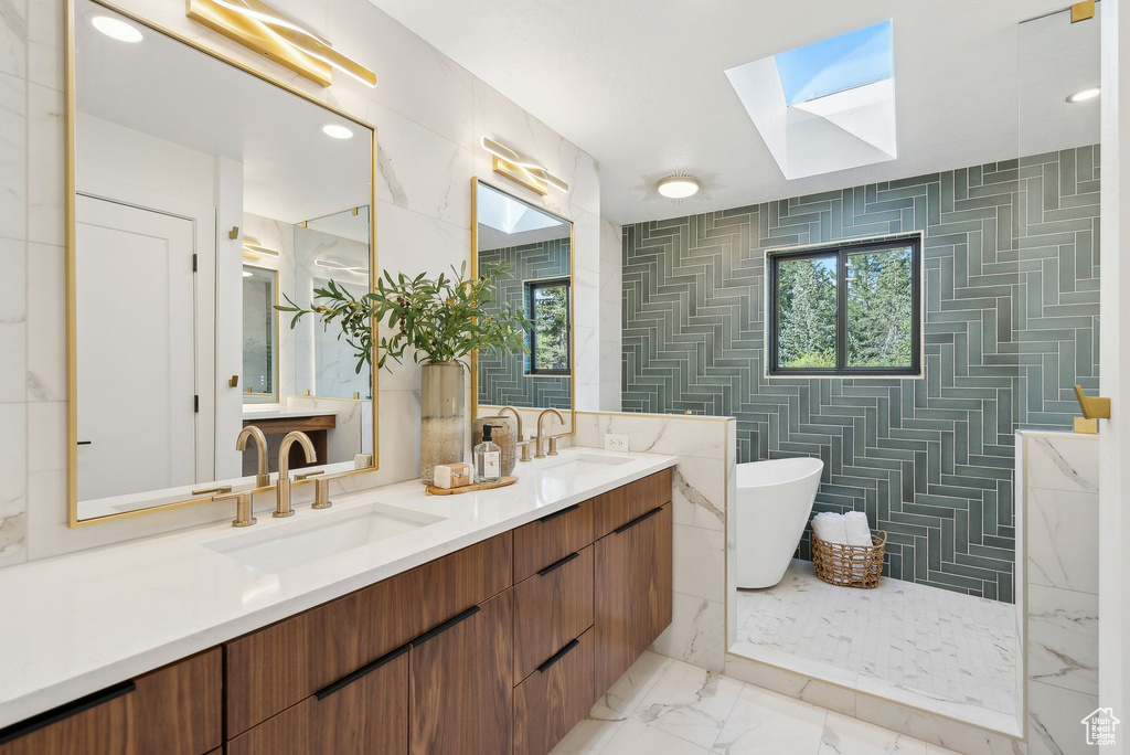 Full bathroom with marble finish floor, a soaking tub, a sink, and a skylight