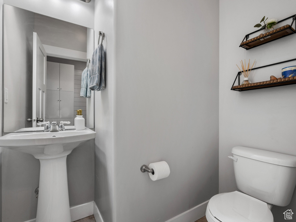 Half bath with toilet, a sink, and baseboards