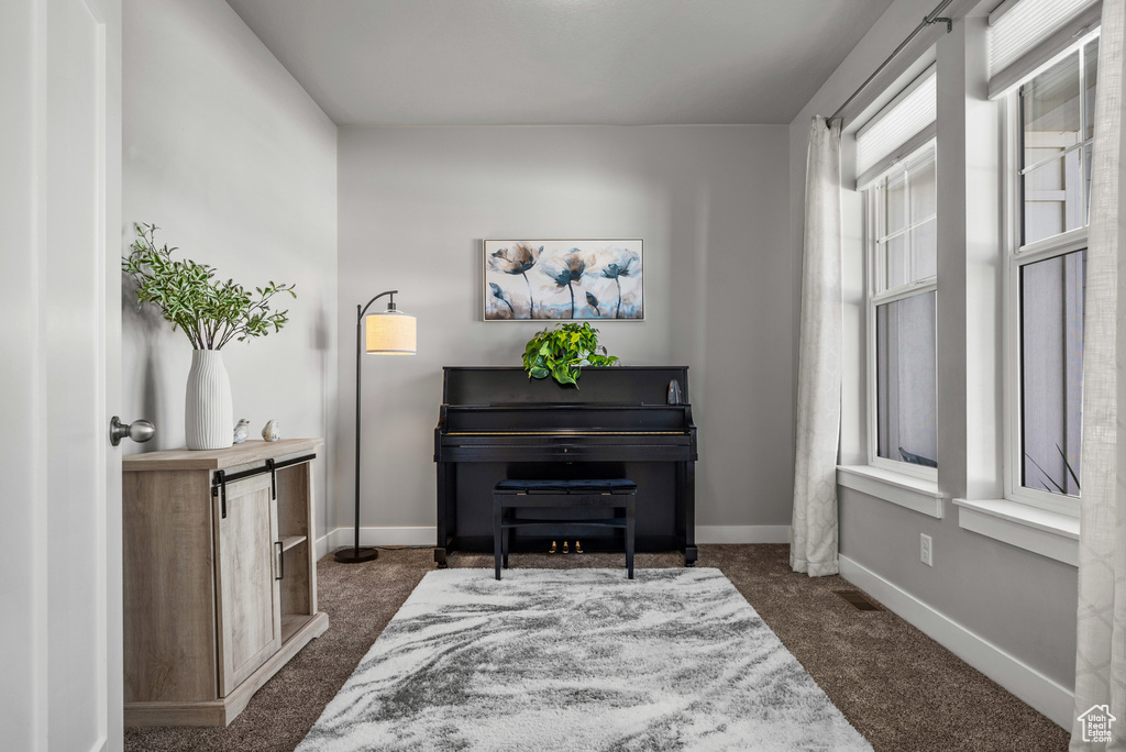 Living area featuring dark colored carpet and baseboards