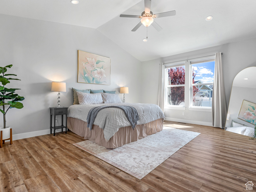 Bedroom with arched walkways, lofted ceiling, baseboards, and wood finished floors