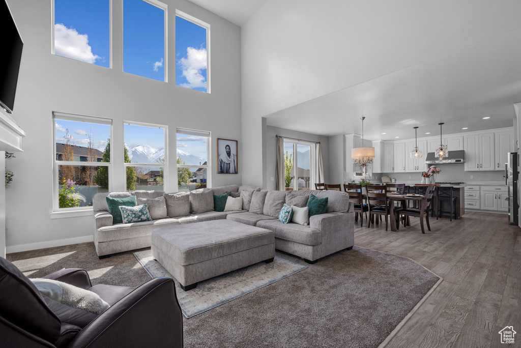 Living area with a towering ceiling, baseboards, wood finished floors, and recessed lighting