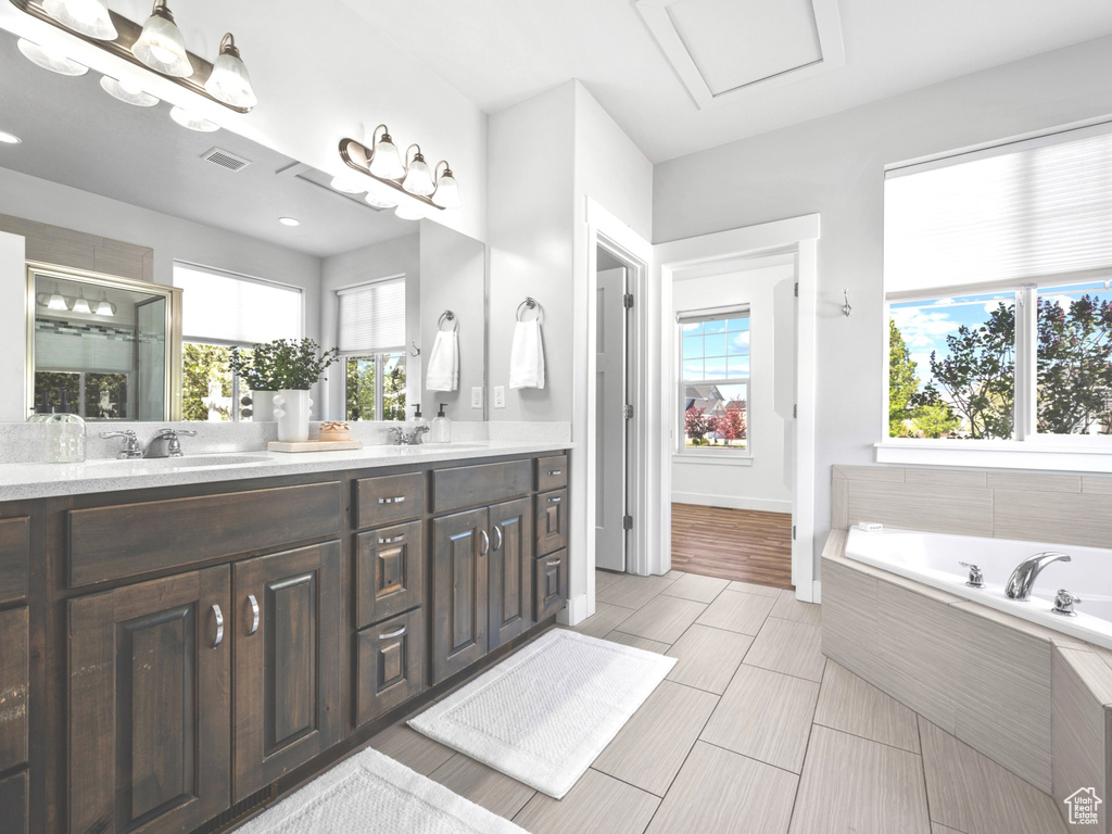 Bathroom with a bath, a wealth of natural light, a sink, and double vanity
