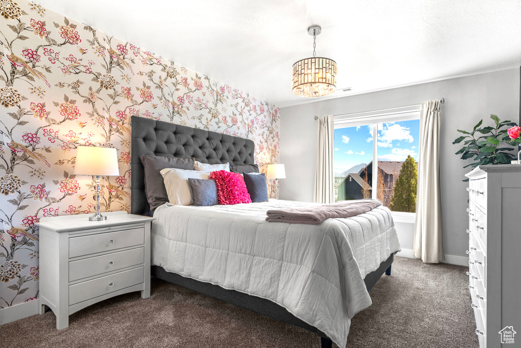 Bedroom with dark carpet, baseboards, a notable chandelier, and wallpapered walls