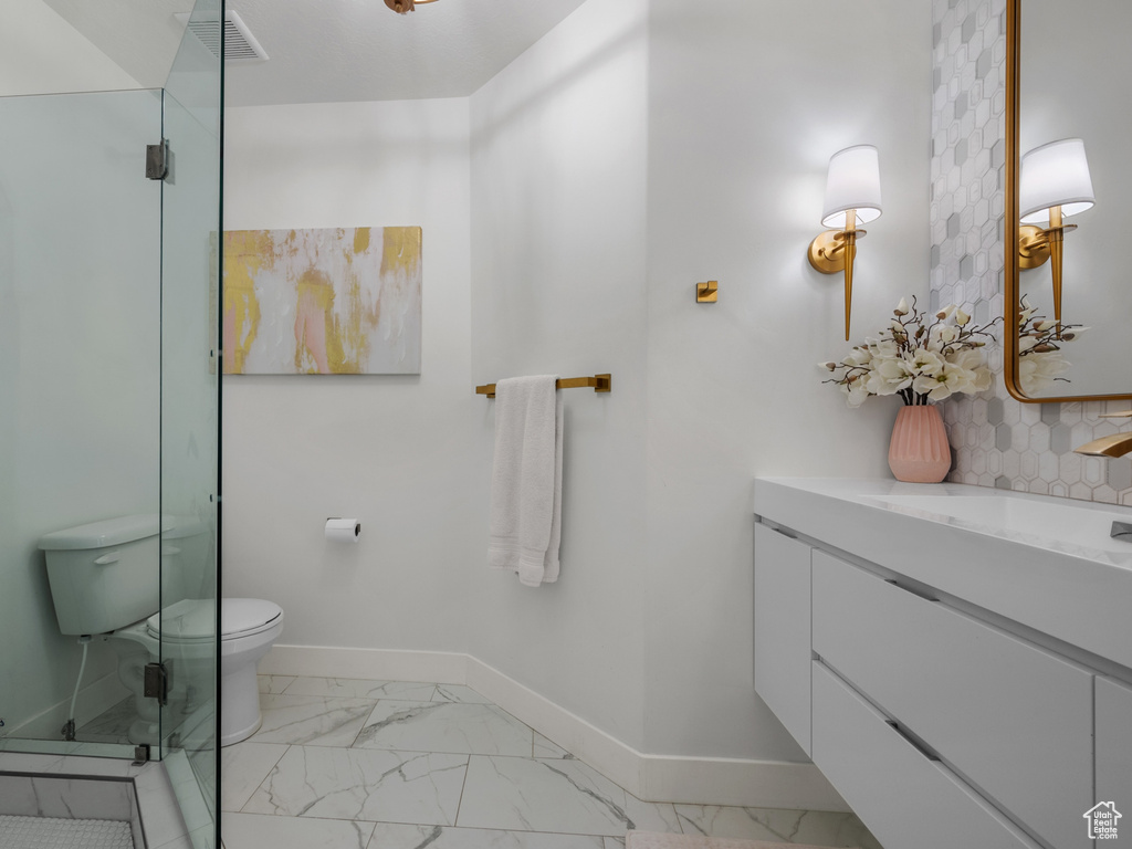 Full bath with a shower stall, marble finish floor, toilet, vanity, and baseboards
