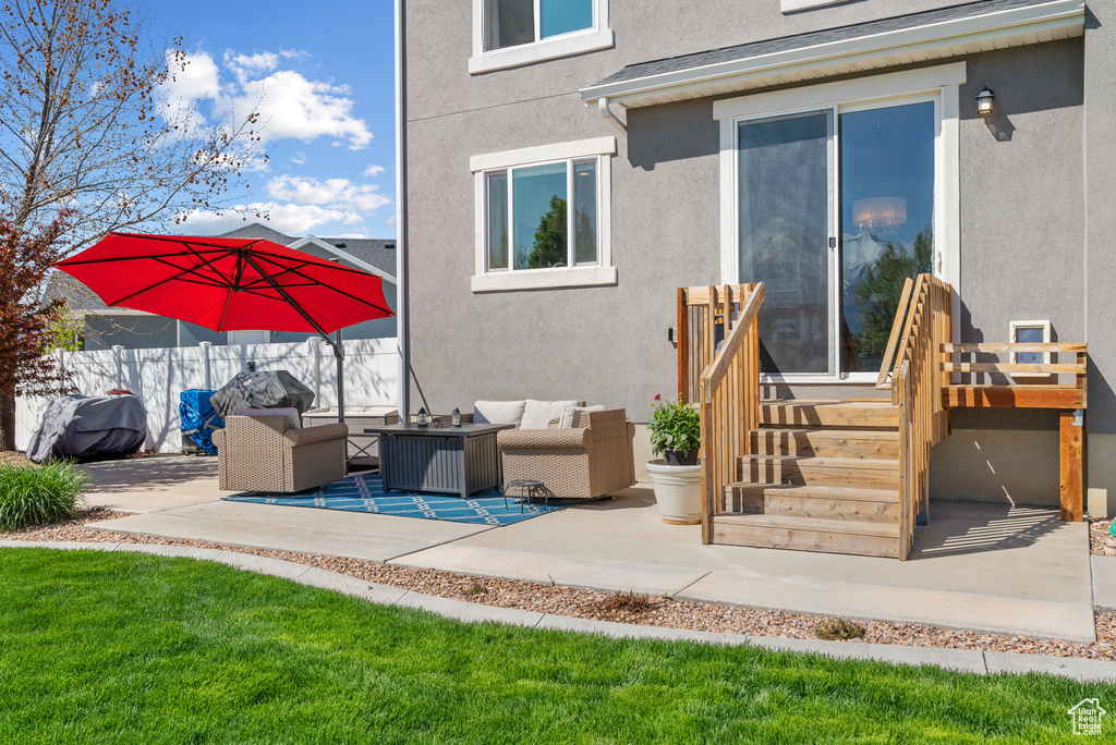 Exterior space featuring fence, a patio area, an outdoor hangout area, and stucco siding