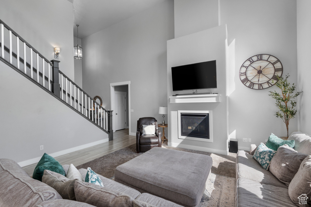 Living area with stairway, a towering ceiling, wood finished floors, baseboards, and a glass covered fireplace
