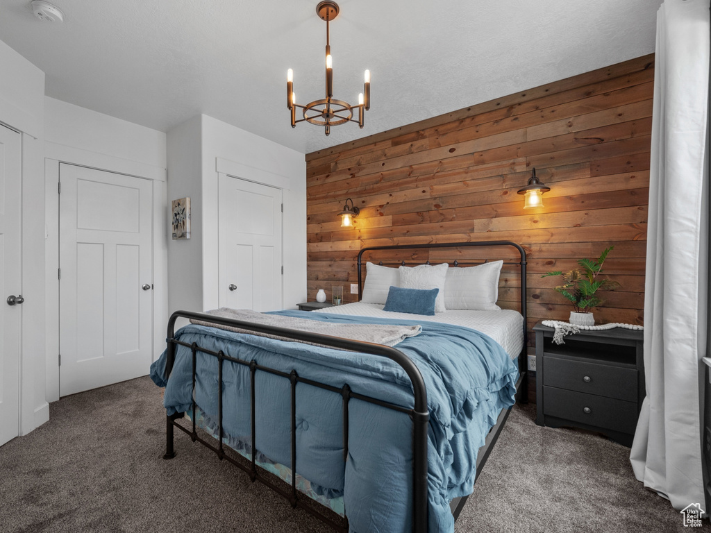 Bedroom with wood walls, carpet flooring, and a chandelier
