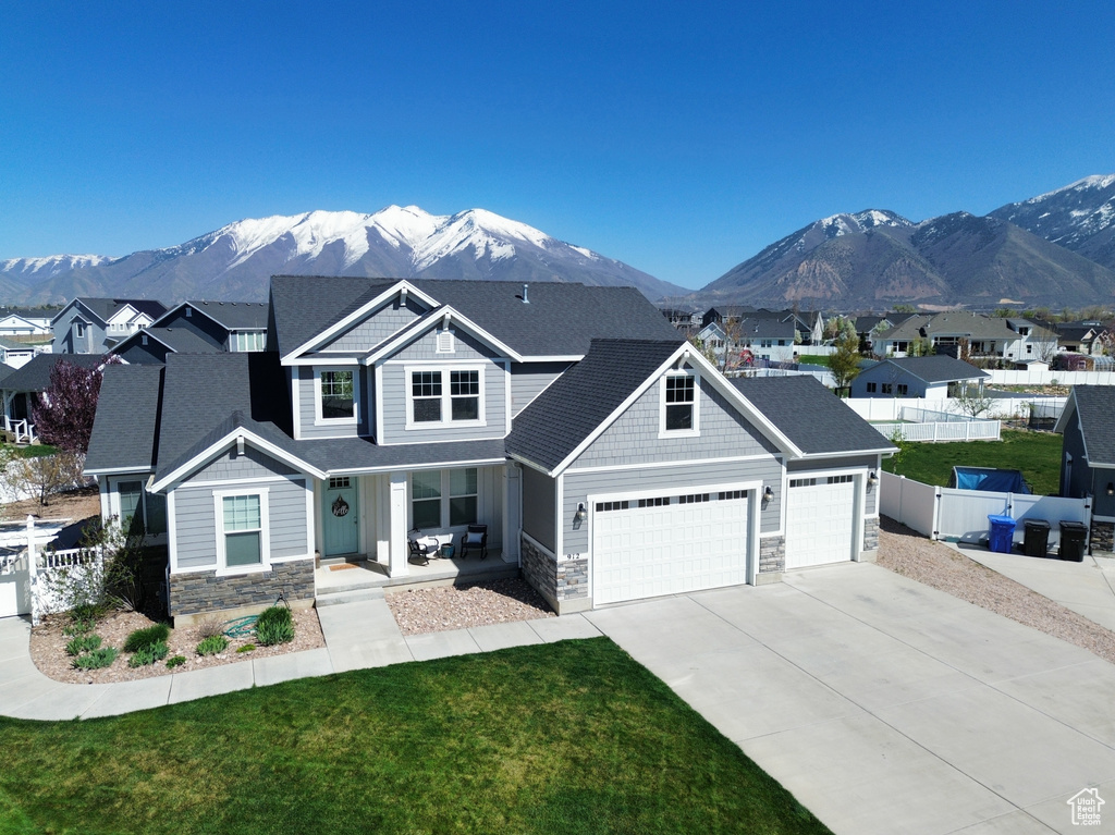 Craftsman house with stone siding, fence, covered porch, and a mountain view