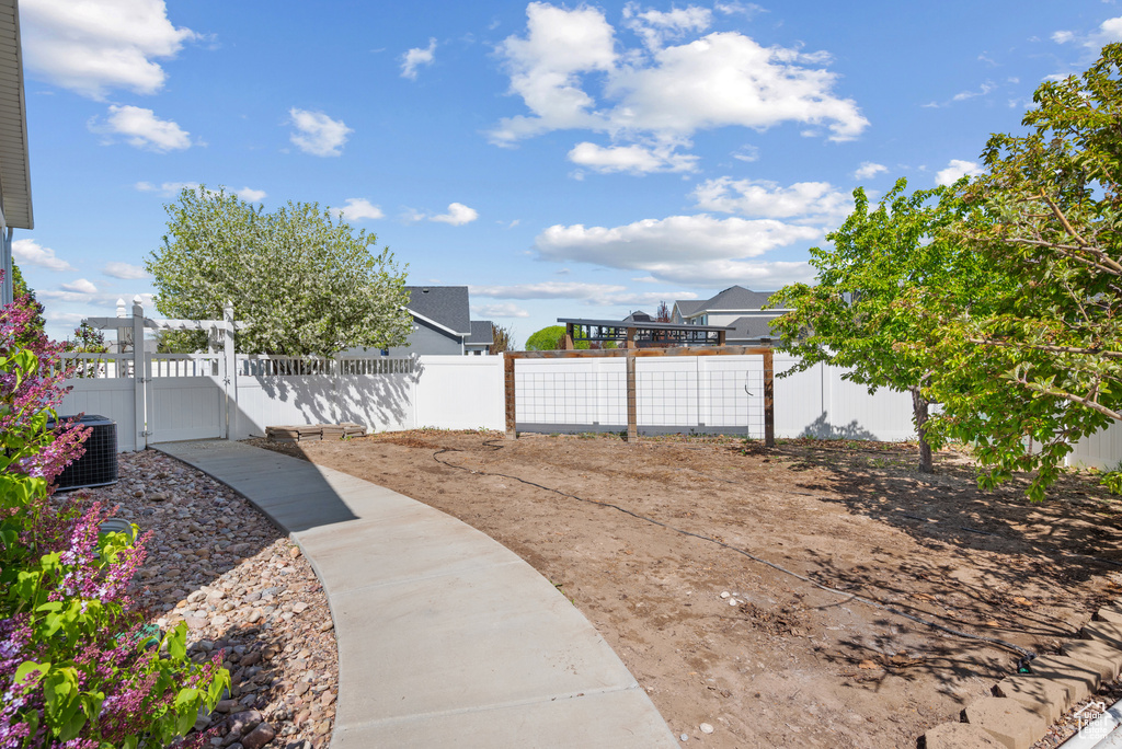 View of yard featuring a gate, central air condition unit, and fence private yard