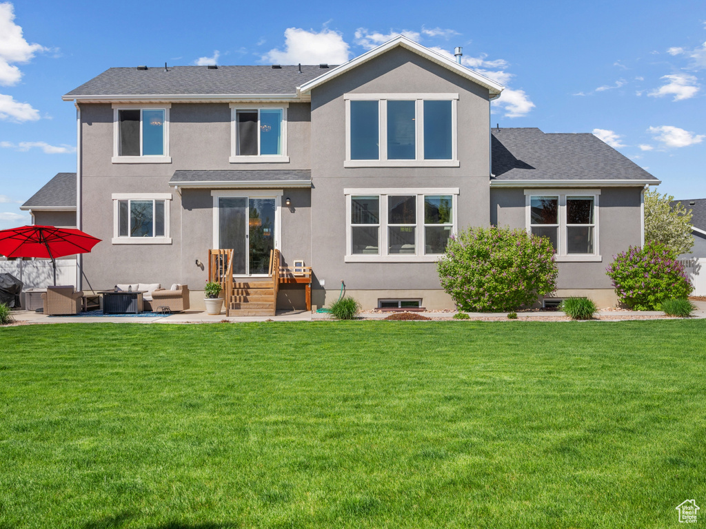 Back of property featuring outdoor lounge area, entry steps, a lawn, and stucco siding