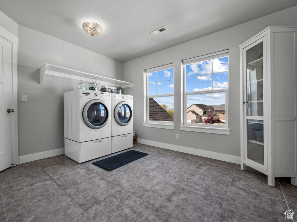 Washroom featuring washing machine and dryer, baseboards, laundry area, and visible vents