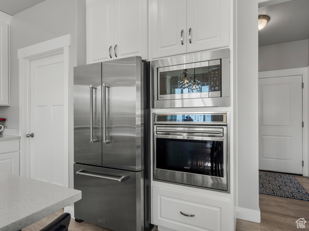 Kitchen with white cabinets, baseboards, appliances with stainless steel finishes, and wood finished floors