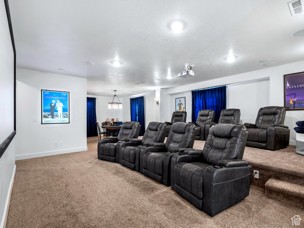 Home theater with visible vents, baseboards, carpet flooring, and a chandelier