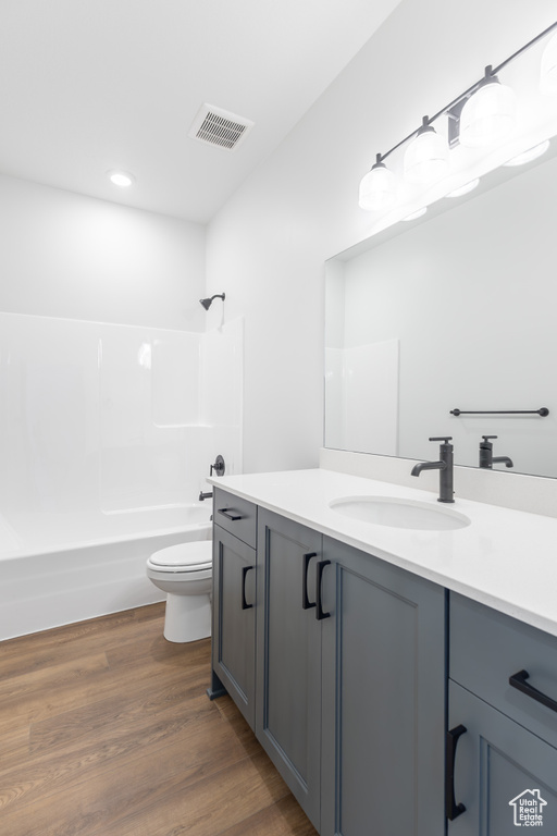 Bathroom featuring vanity, shower / tub combination, wood finished floors, and recessed lighting