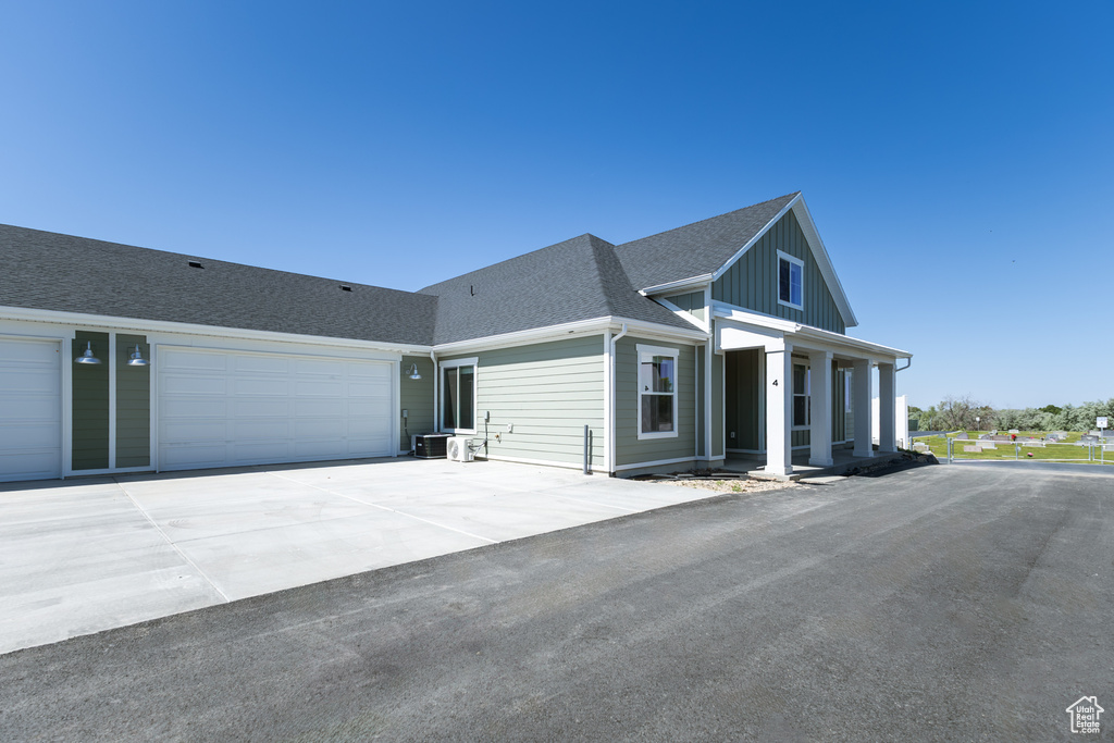 View of front of home with a shingled roof, an attached garage, driveway, and board and batten siding