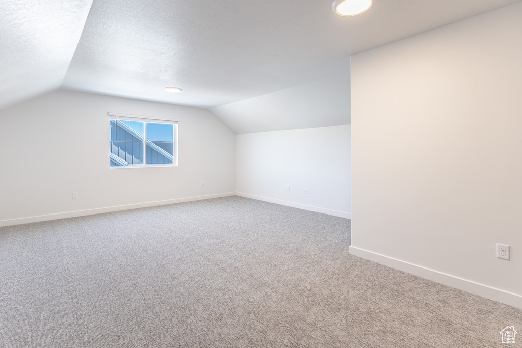 Bonus room featuring vaulted ceiling and carpet floors