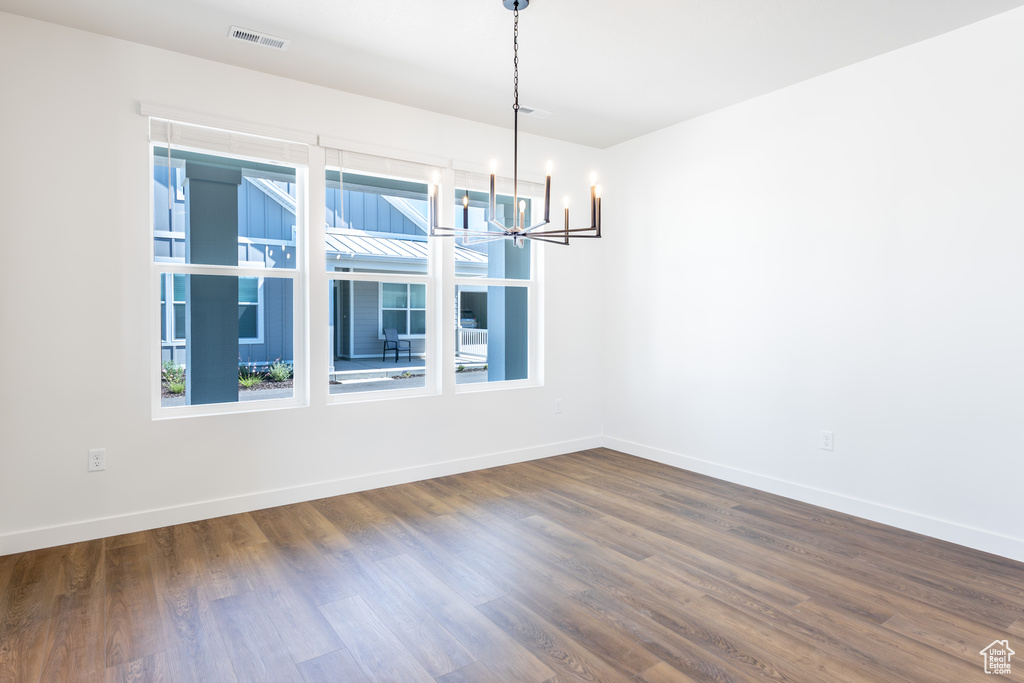 Spare room featuring a chandelier and dark wood finished floors
