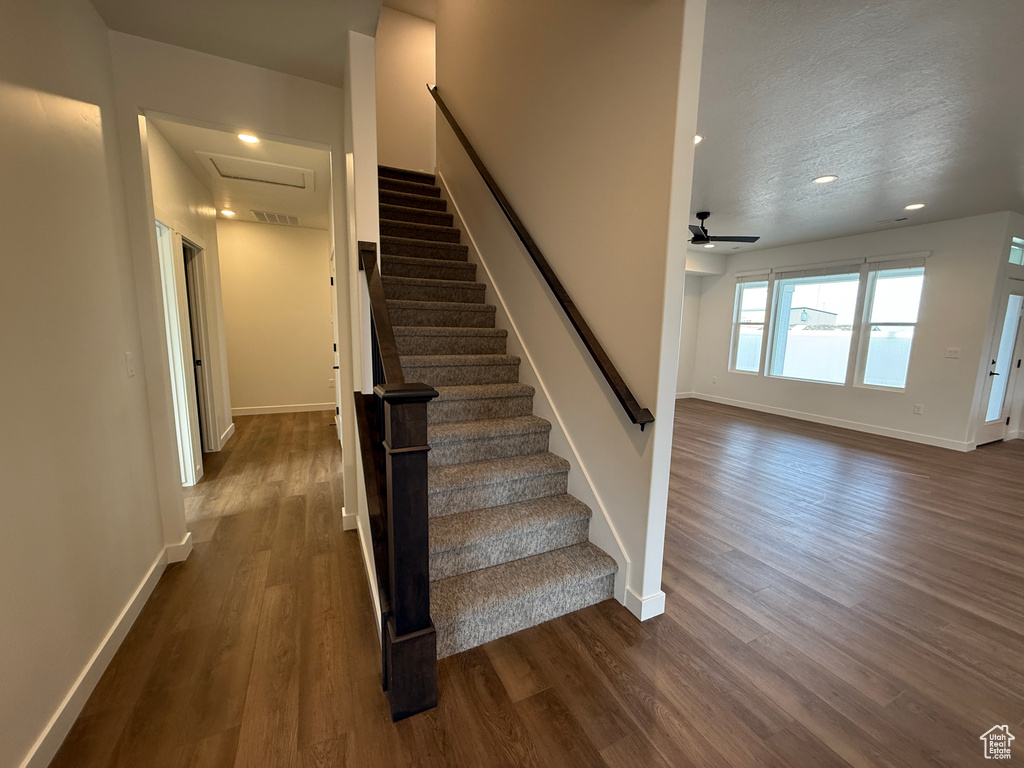Stairs featuring wood finished floors, baseboards, a ceiling fan, recessed lighting, and a textured ceiling