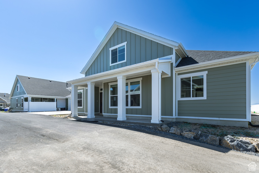 View of front of home featuring board and batten siding, covered porch, and roof with shingles