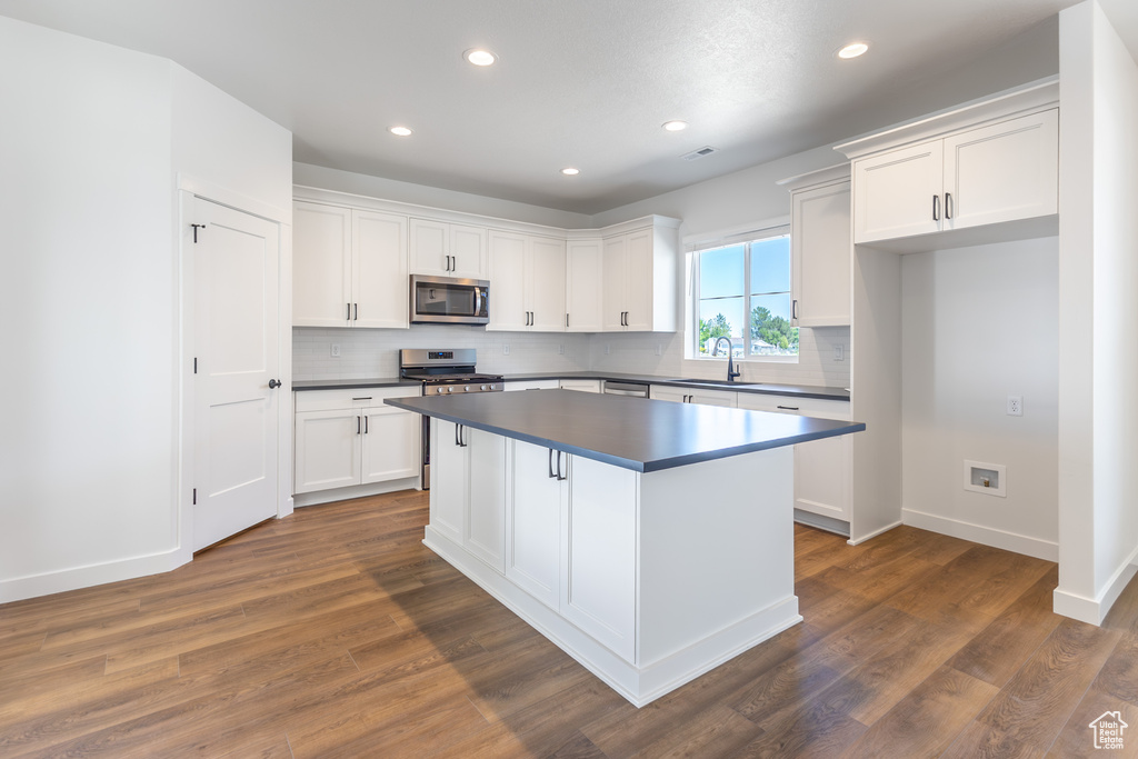 Kitchen with stainless steel appliances, dark countertops, tasteful backsplash, white cabinetry, and recessed lighting
