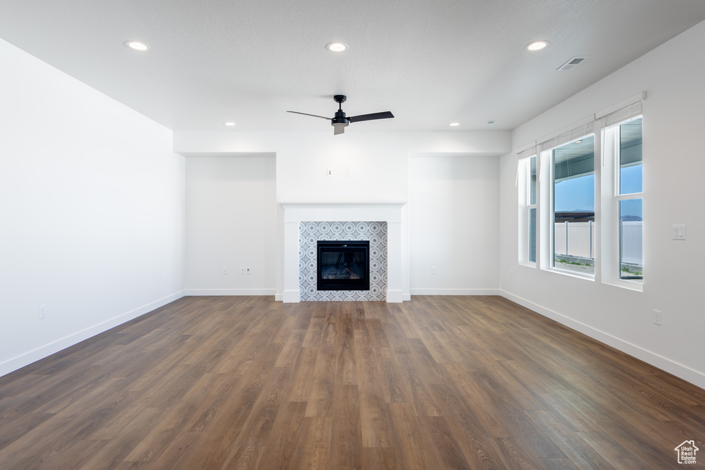 Unfurnished living room with a ceiling fan, recessed lighting, dark wood-style floors, and a tiled fireplace