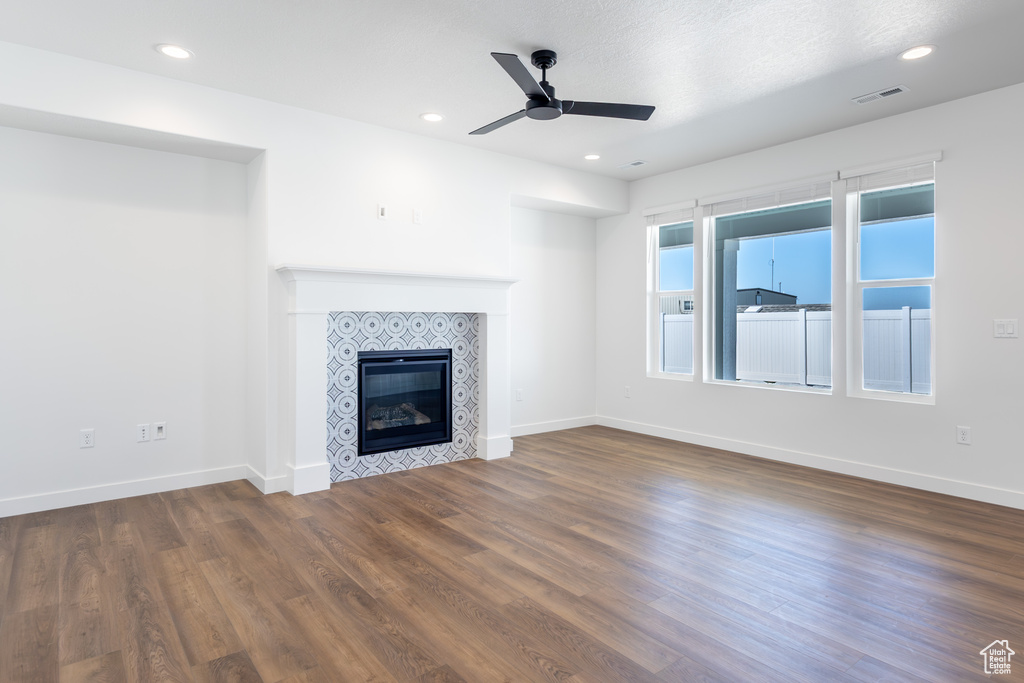 Unfurnished living room featuring ceiling fan, wood finished floors, a tiled fireplace, and recessed lighting