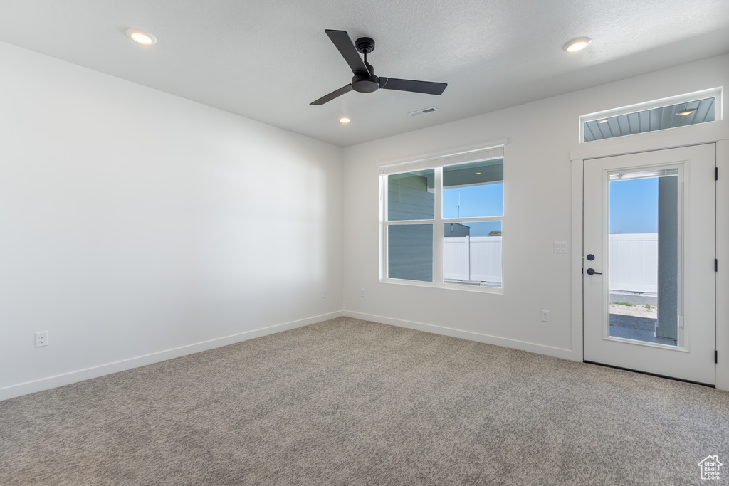 Empty room with carpet floors, healthy amount of natural light, ceiling fan, and recessed lighting