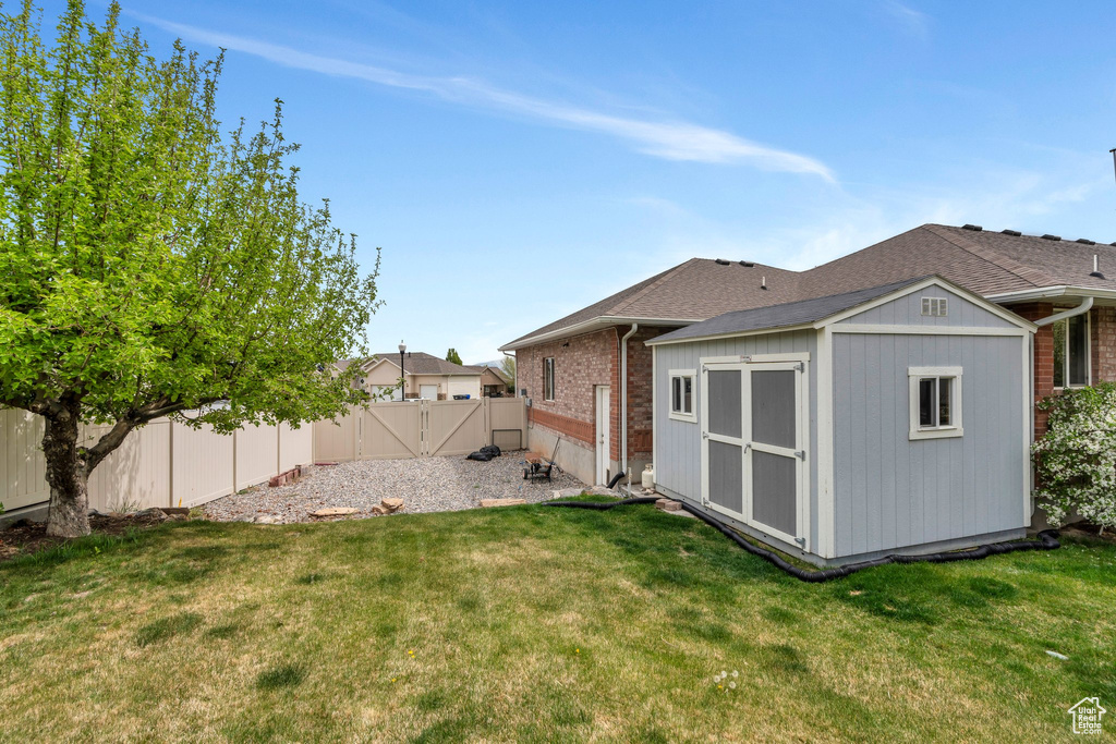 Back of house with a fenced backyard, an outdoor structure, a yard, and a storage unit