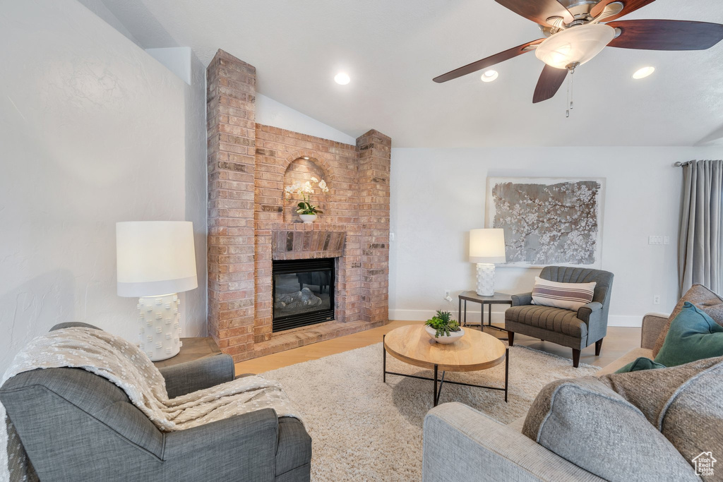 Living area featuring recessed lighting, vaulted ceiling, a ceiling fan, baseboards, and a fireplace